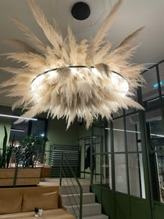 a chandelier with feathers hanging from it's ceiling in an office building