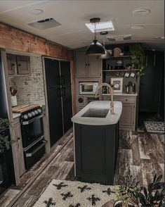 a kitchen with black appliances and wooden flooring in an airstream style home or rv