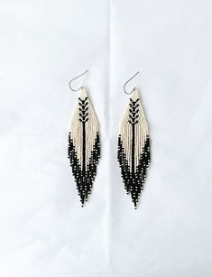 I have just loved creating these woven treasures. These simple, elegant earrings have been handwoven one bead at a time using Czech glass seed beads, bugle beads and strong synthetic string. They are finished with a stainless steel ear wires. They are light and delicate and perfect for any occasion. Colour: Eggshell/Cream and Black Length: 12.5 cm with a 13.5 cm drop Width: Triangular Shape 3 cm Beaded fringe earrings have a memory so please either hang or lay flat when not wearing. For other ea Silver Beaded Earrings, Small Beaded Earrings, Simple Elegant Earrings, Brick Stitch Pattern Earring, Flower Beaded Earrings, Red Beaded Earrings, Fringe Beaded Earrings, String Earrings, Silver Bead Earrings