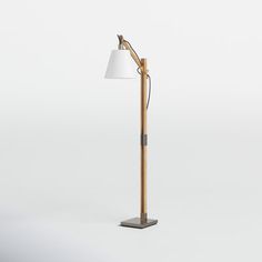 a wooden floor lamp with a white shade on the top, and a metal base