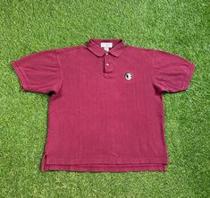 a red polo shirt laying on the grass