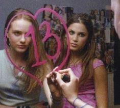 two young women are holding up the numbers in front of their faces and writing on them