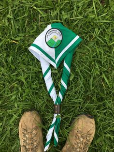 there is a green and white hat on top of the grass next to hiking boots