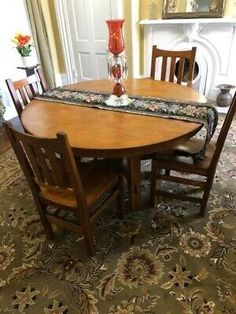 a dining room table with four chairs and a vase on top of it in front of a fireplace