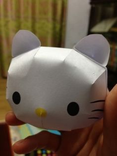 someone is holding up a paper hello kitty ornament to show it's face