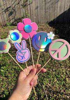 a hand holding up some paper flowers with peace signs and flowers in the middle on them