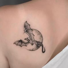 a woman's back with a tattoo on her shoulder and an image of a bat