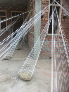 there are two large white hammocks in the room with brick walls and windows