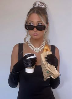 a woman wearing black gloves and holding a coffee cup in her right hand while wearing a tiara