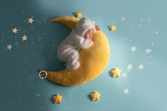 a baby sleeping on the moon with stars around it