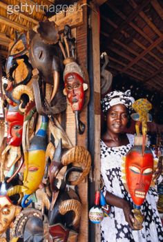 a woman standing in front of a wall with masks on it