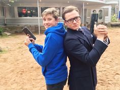 two people standing in front of a house holding remotes and pointing at the camera