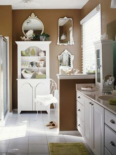 a bathroom with white cabinets and brown walls