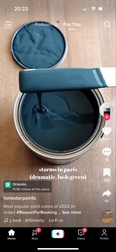 an open can of paint sitting on top of a wooden table next to a smart phone