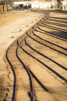 an empty train track with no cars on it in the middle of nowhere near some buildings