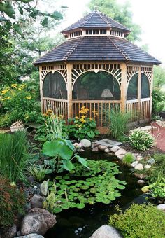 a gazebo surrounded by water lilies and other greenery in a garden area