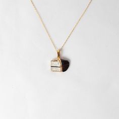 a gold necklace with a black and white piece of jewelry hanging from it's center