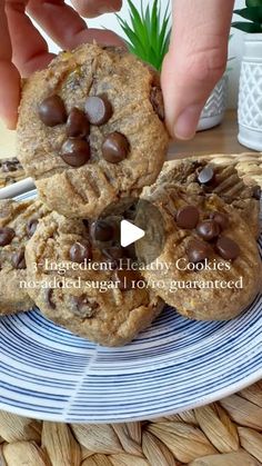 chocolate chip cookies on a blue and white plate with a hand reaching for one cookie