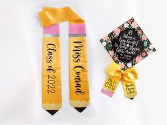 two yellow graduation sashes with ribbons on them next to a black and white cap