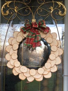 a wreath made out of wood slices with a bow hanging on it's front door