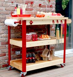 an outdoor bar cart with drinks and snacks on the outside deck, next to a brick wall