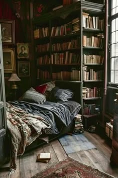 a bed sitting in front of a book shelf filled with books on top of a wooden floor