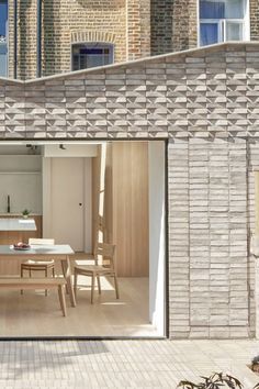 an open kitchen and dining room are seen through the sliding glass doors on this brick building