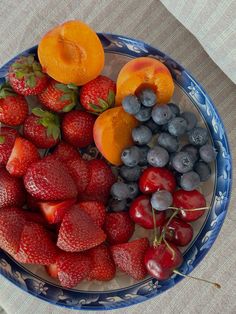 a plate with strawberries, oranges and blueberries on it