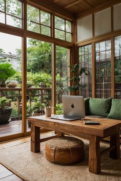 a laptop computer sitting on top of a wooden table in front of large glass windows