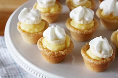 small cupcakes with whipped cream on top sit on a white plate