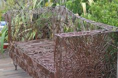 a bed made out of branches sitting on top of a wooden floor next to plants