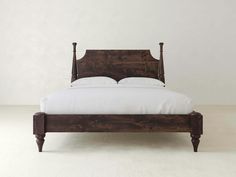 a wooden bed with white sheets and pillows