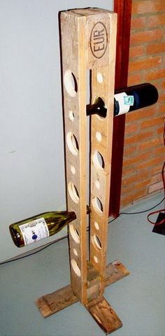 a wooden wine rack with two bottles on it next to a brick wall and speaker