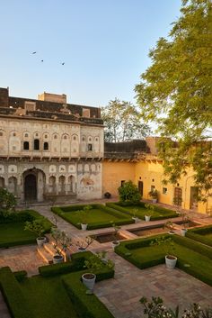 an old building with lots of green plants in the courtyard and on top of it