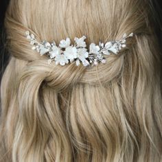 a woman with blonde hair wearing a white flowered headpiece in her hair, close up