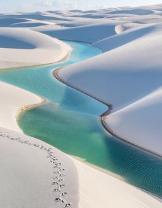 an aerial view of the white sands and blue water in the desert, with footprints on the sand