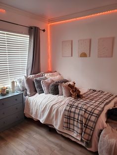 a bed sitting in a bedroom next to a window with lights on the side of it