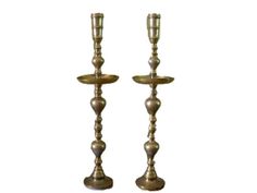 two metal candlesticks sitting next to each other