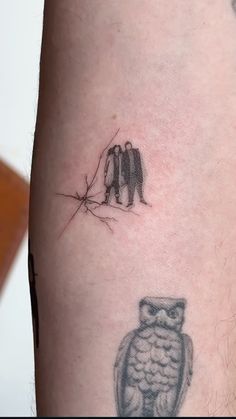 an owl tattoo on the arm with two people standing behind it and one person looking at something