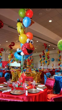 a room filled with tables covered in red and blue table cloths, plates and balloons