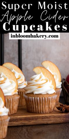 cupcakes topped with white frosting and cinnamon on a cutting board next to an apple