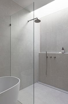 a white bathtub sitting next to a walk in shower under a skylight on top of a tiled wall