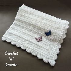 two butterflies are sitting on the edge of a crochet dishcloth that is white