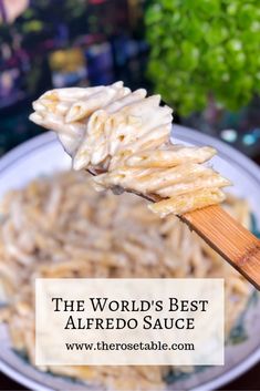 the world's best alfredo sauce is on a wooden spoon with noodles in it