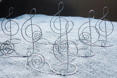 four metal wire sculptures sitting on top of a white cloth covered ground with snow around them