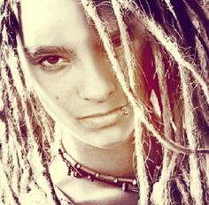 a man with dreadlocks on his head is staring at the camera while wearing a chain around his neck