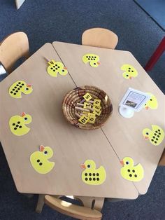 a wooden table with yellow rubber ducks on the top and numbers cut out to spell out letters