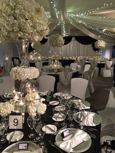 the tables are set up with white flowers and silverware for an elegant wedding reception