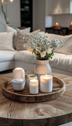 a table with candles and flowers in a vase on top of it next to a couch