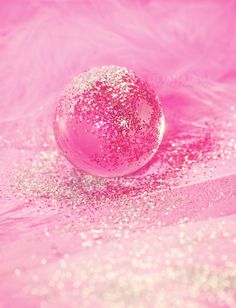 a pink ball sitting on top of a table next to some white and pink feathers